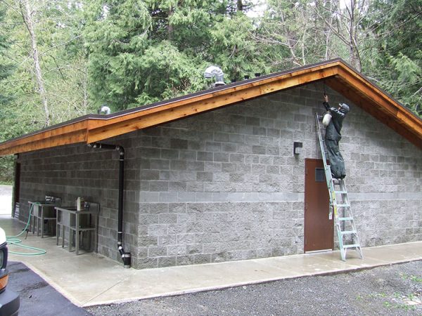 Painter Staining Wood On Exterior Of Building